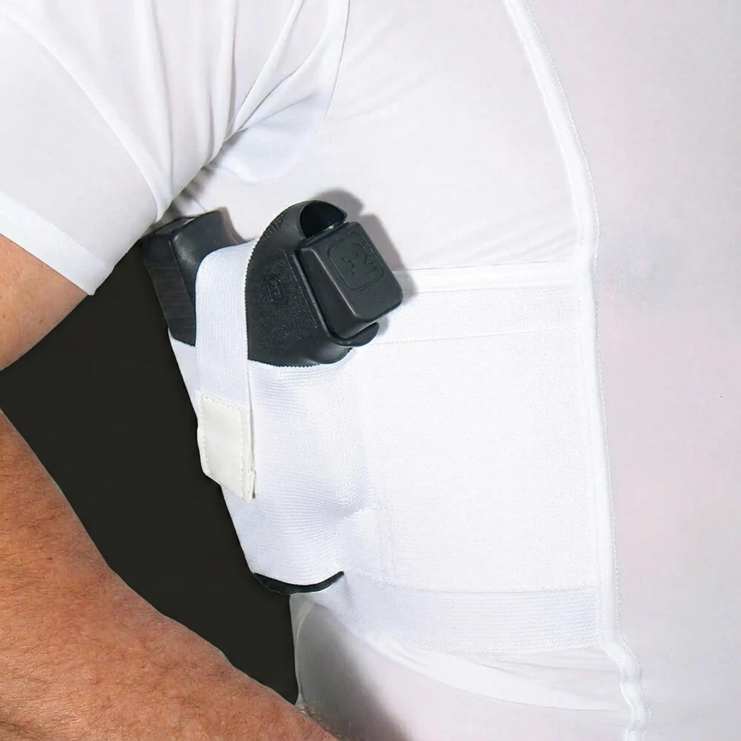 A handgun tucked into a white underarm holster built into a t-shirt.