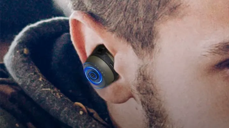 Close-up of a person wearing a wireless earbud with blue light.