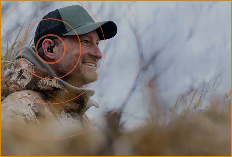 Man in camouflage and cap with ear protection, outdoors, with circular overlay.