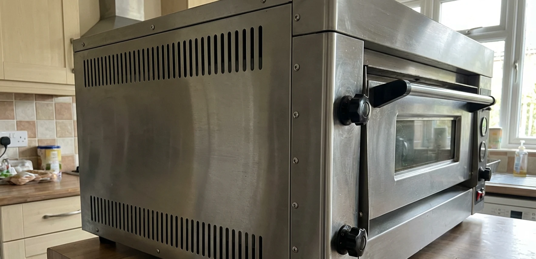 Stainless steel oven with black knobs in a kitchen setting.