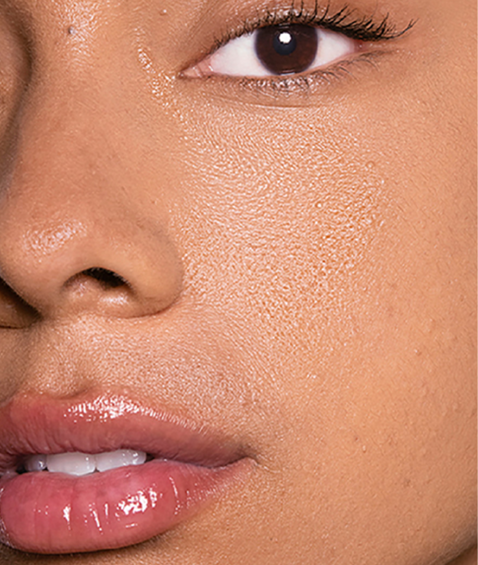 An extreme close-up of a person's face, focusing on the dewy skin, eye, nose, and lips.