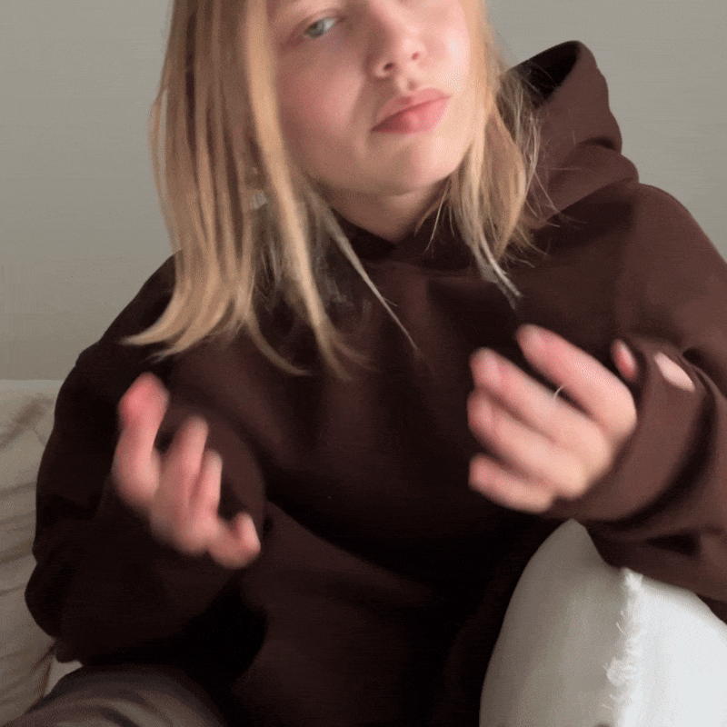 Person in a brown hoodie gesturing with hands.