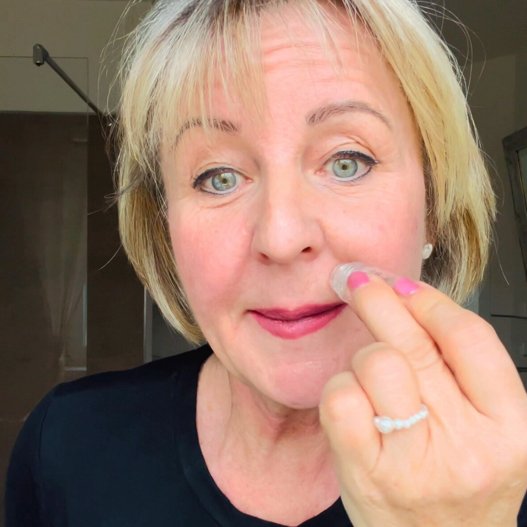 Person applying makeup to their cheek with a small applicator.