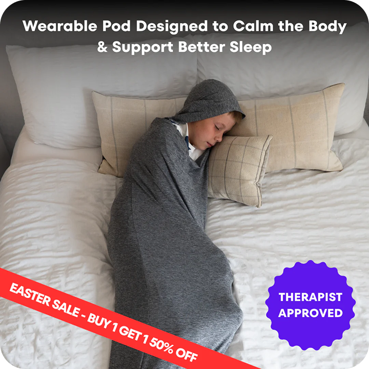 A boy sleeps peacefully in a bed while cocooned in a grey, hooded wearable pod.