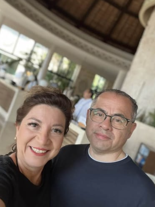 Two people smiling indoors with a blurred background.