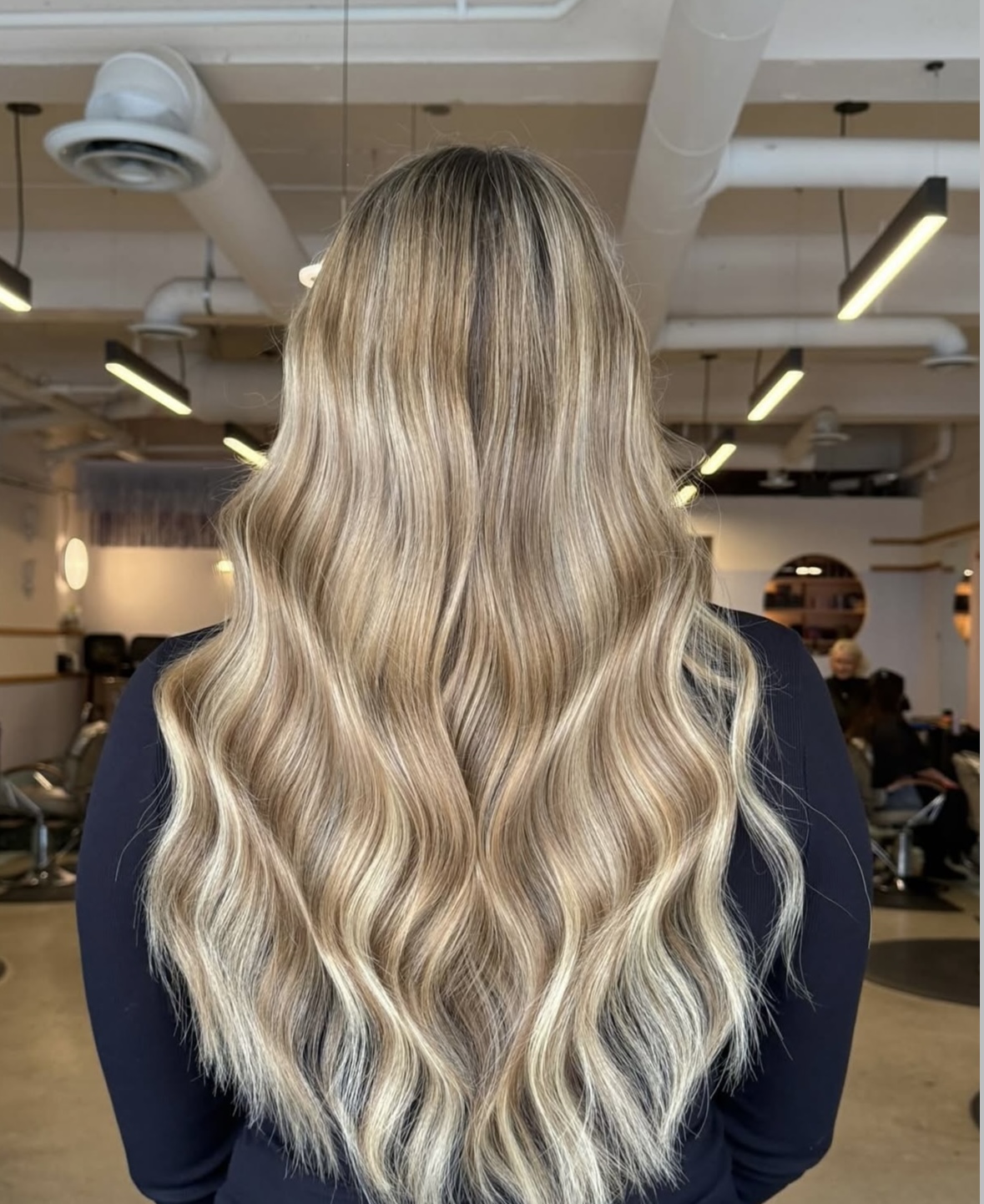 Person with long, wavy blonde hair in a salon setting.