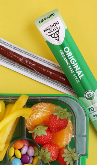 Organic beef stick with fruits and candies on a yellow background.