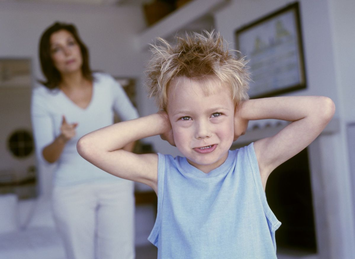 Child covering ears with woman in background pointing.