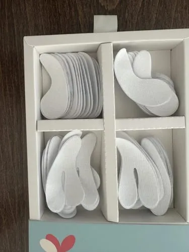 An open box with four compartments filled with stacks of white, shaped pads.