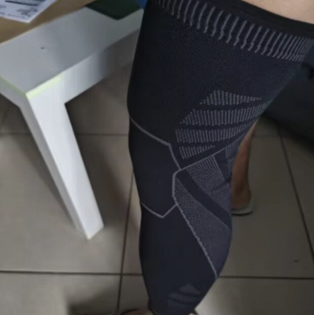 Person wearing black patterned leggings standing on a tiled floor near a white table.