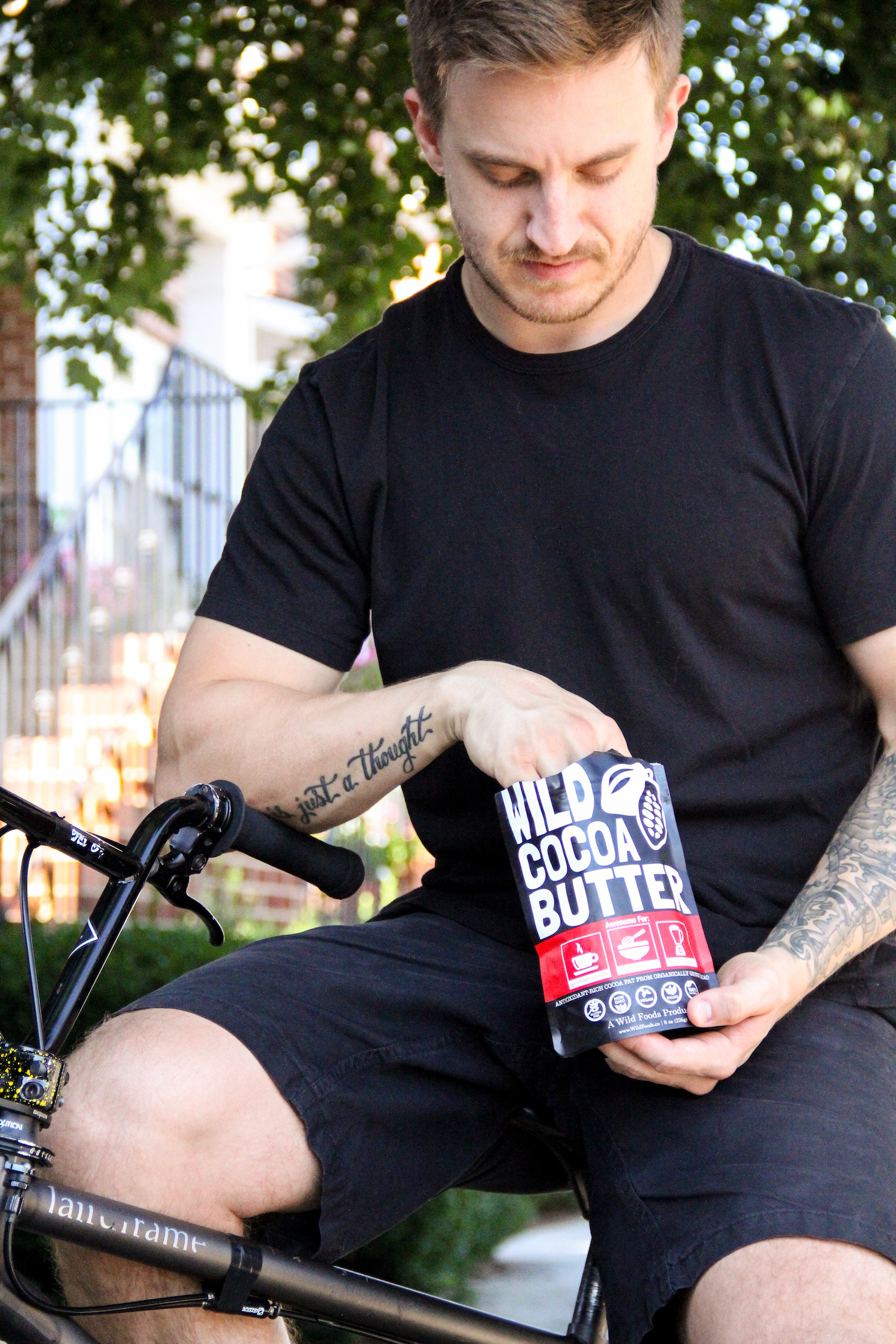 Person in black shirt holding a bag of wild cocoa butter on a bicycle.