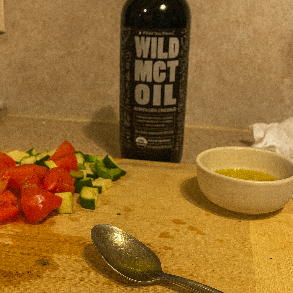 Chopped vegetables and a spoon on a cutting board with MCT oil bottle and a small bowl.