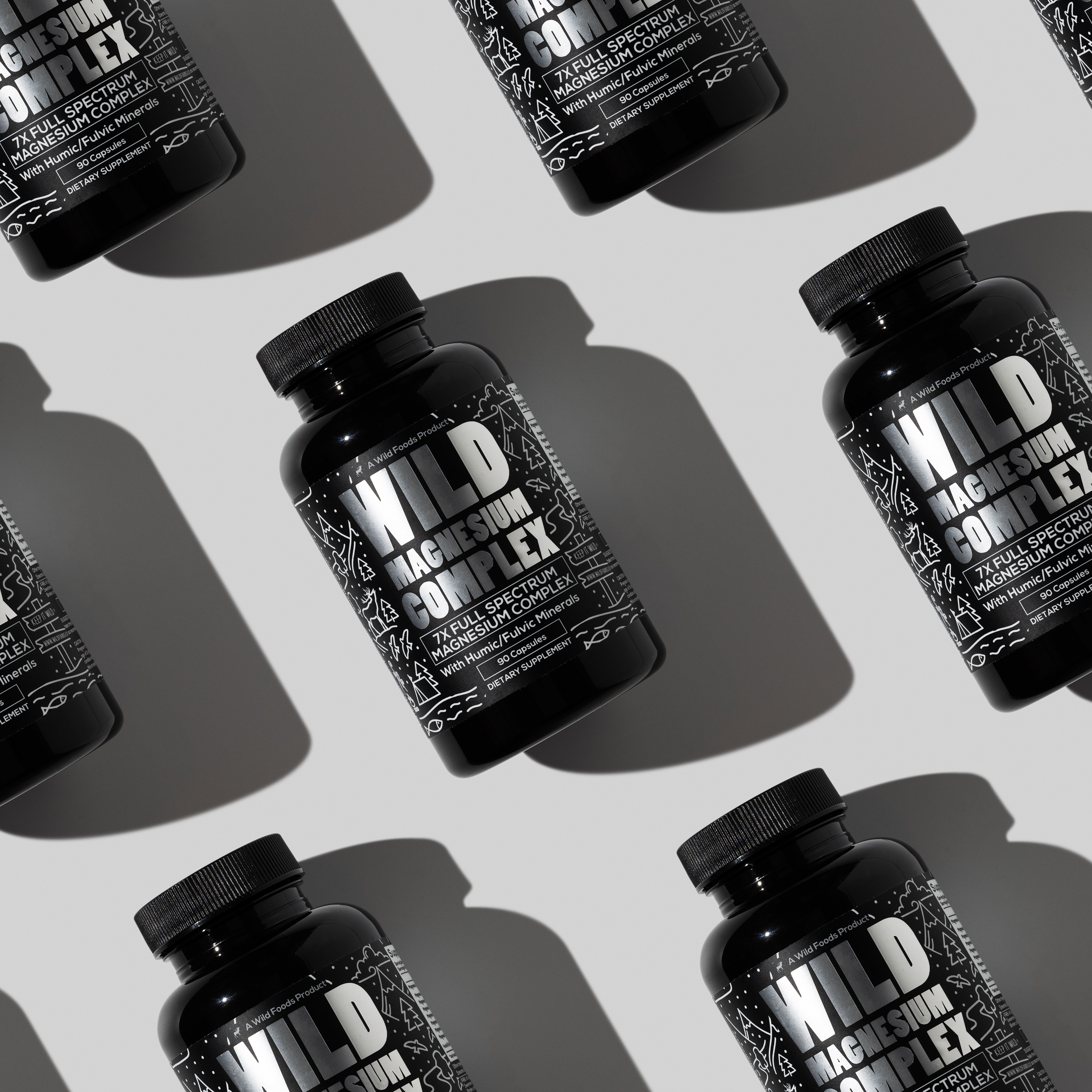 Black bottles labeled 'Wild Magnesium Complex' arranged diagonally on a light background.