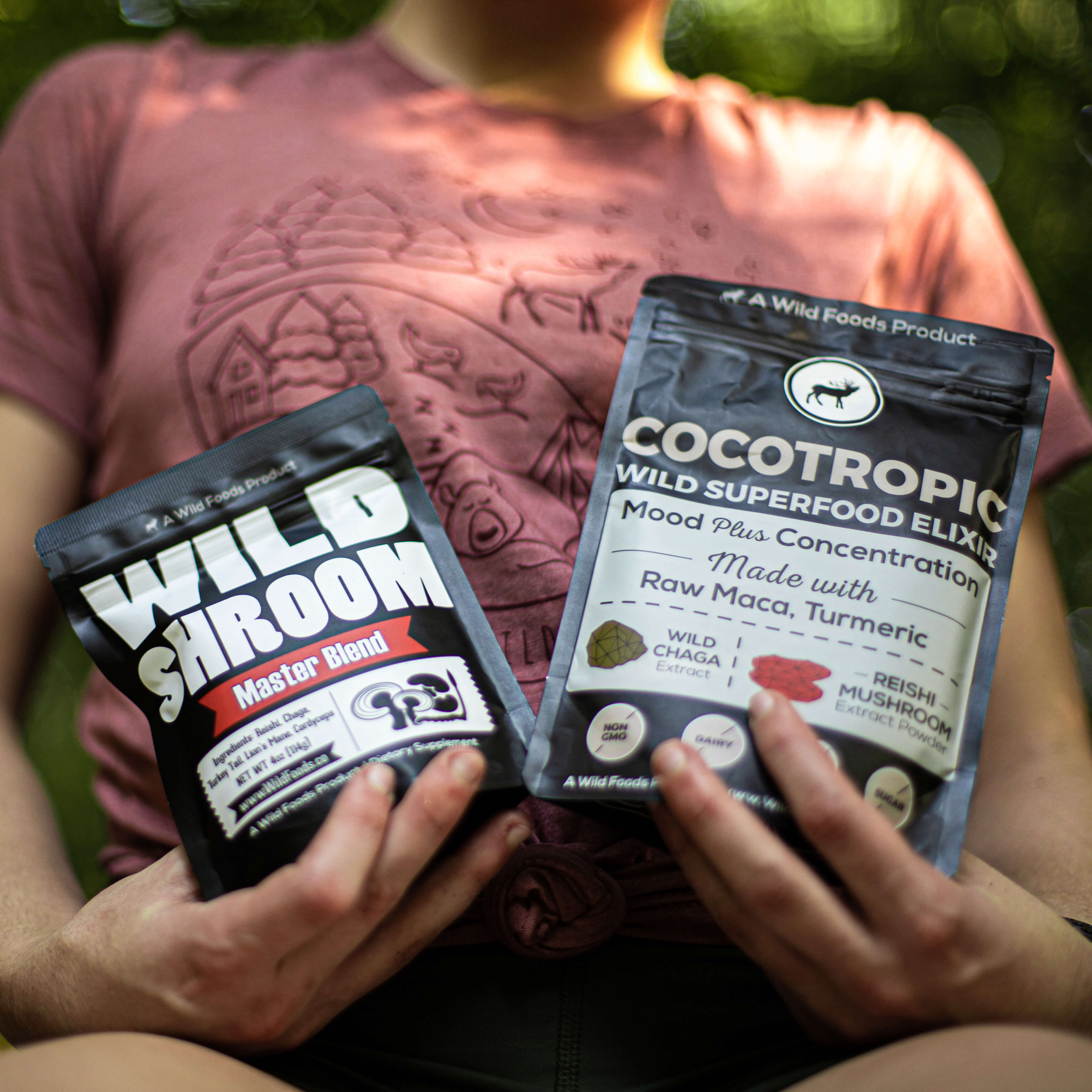 Person holding two bags of superfood products in a forest setting.