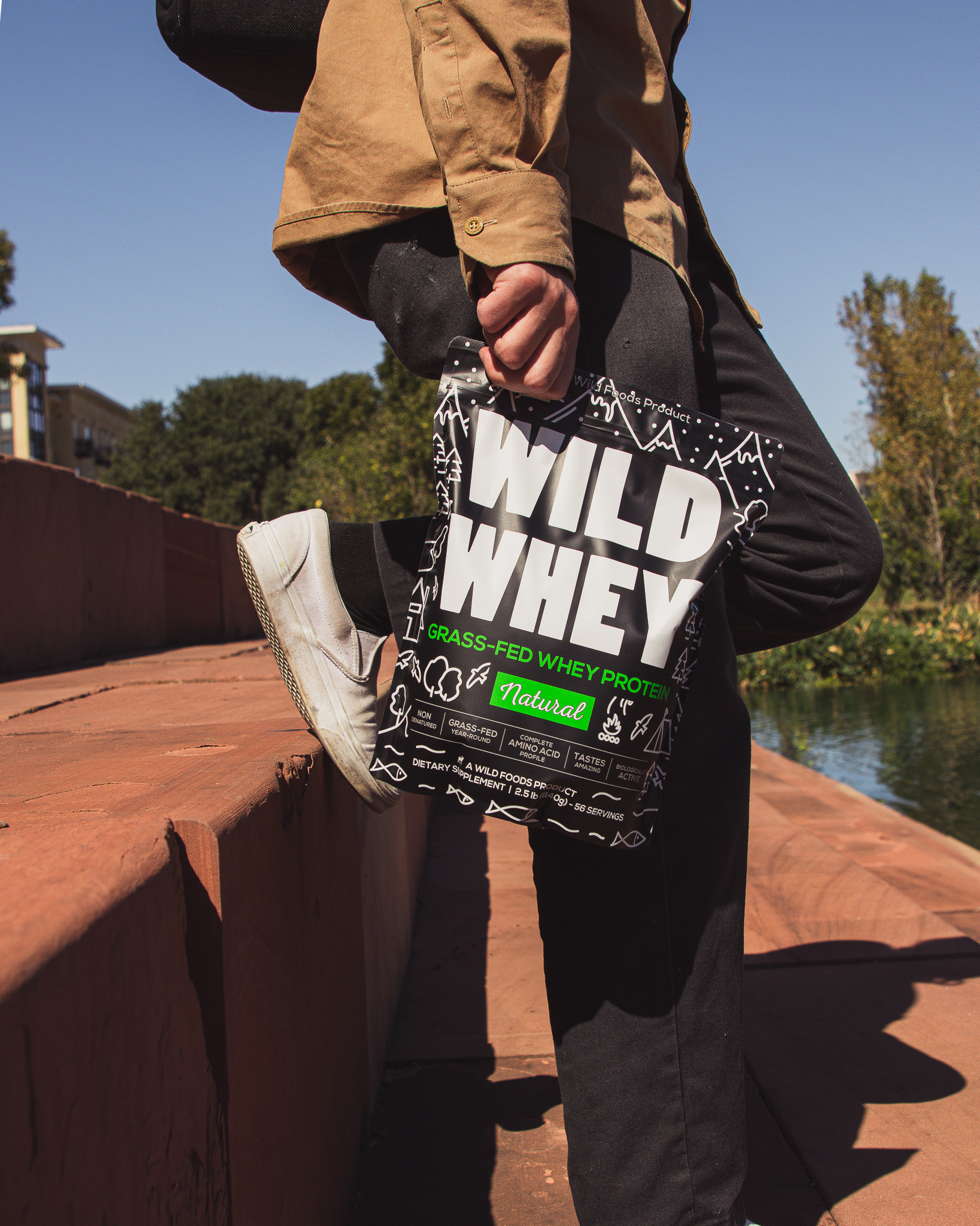 Person holding a bag of grass-fed whey protein outdoors.