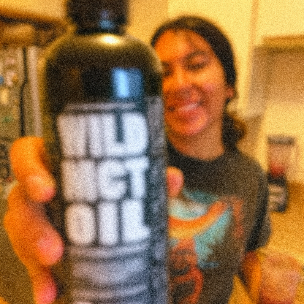 Person holding a bottle labeled 'Wild MCT Oil' with a blurred background.