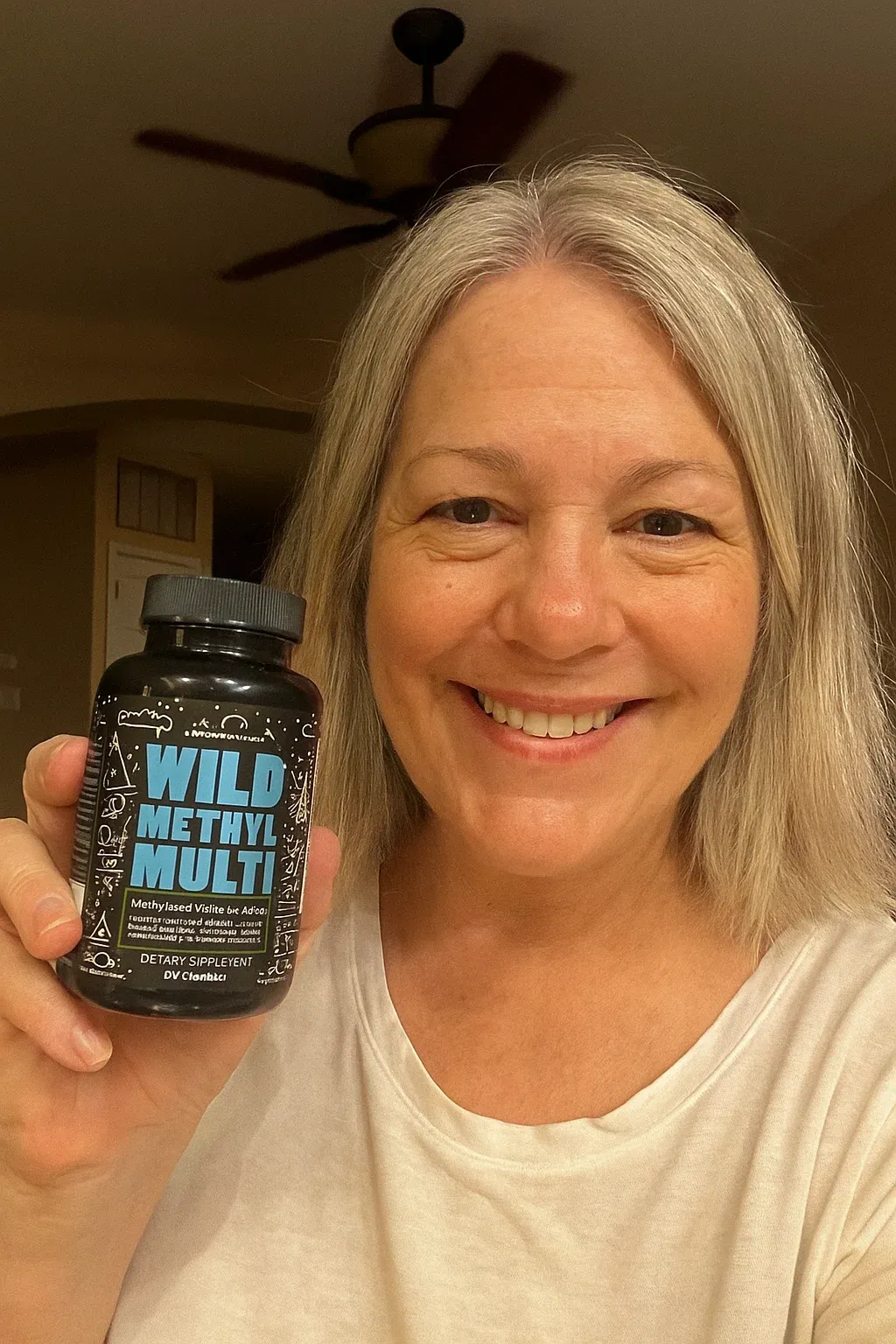 Person smiling, holding a bottle labeled 'Wild Methyl Multi'.