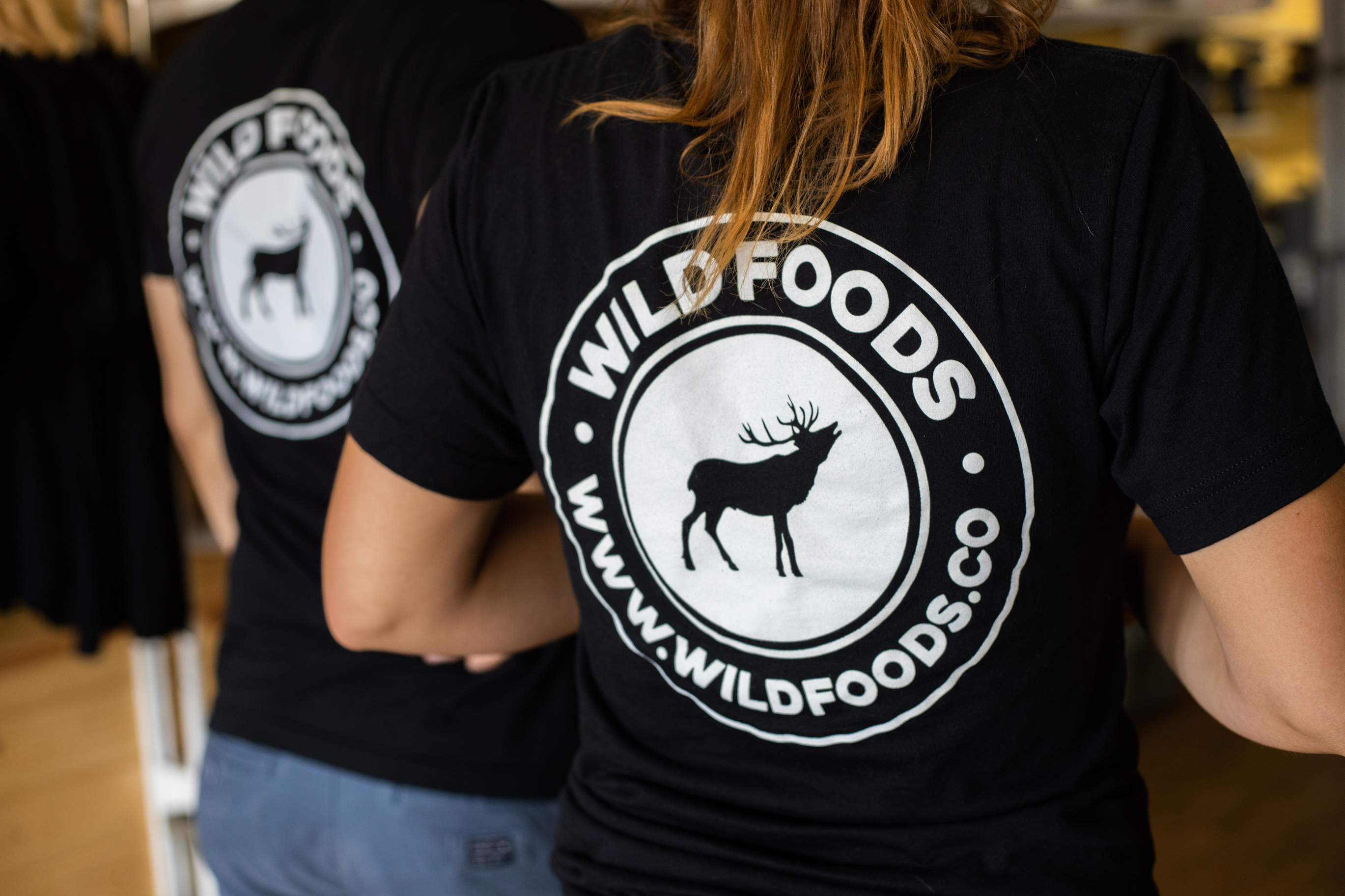 Two people wearing black Wildfoods logo shirts.