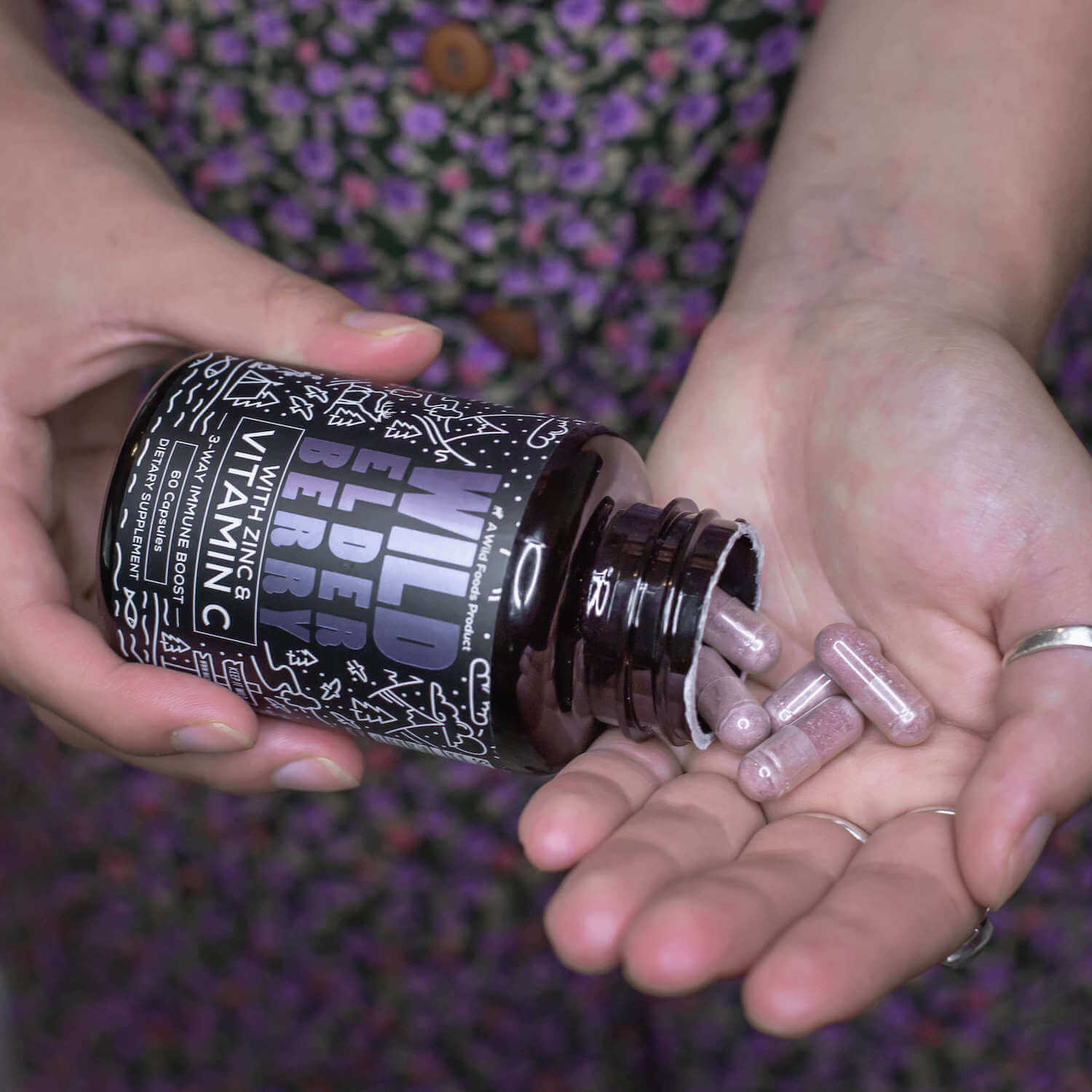 Person holding a bottle of wild elderberry vitamin capsules.