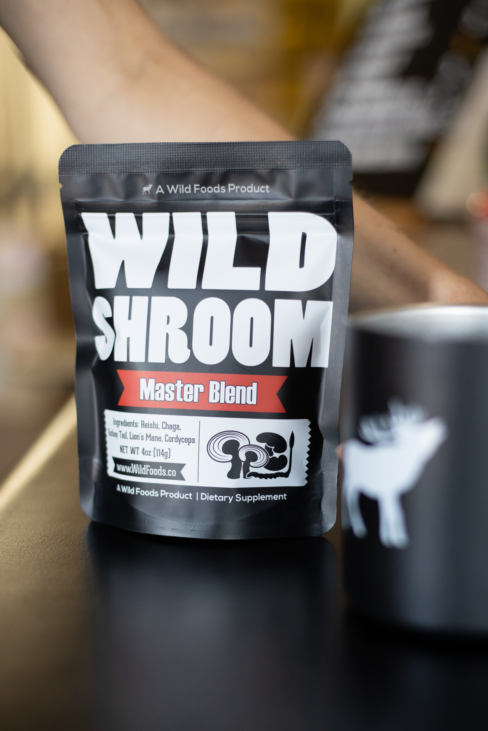 A bag labeled 'Wild Shroom Master Blend' with a blurred cup beside it.