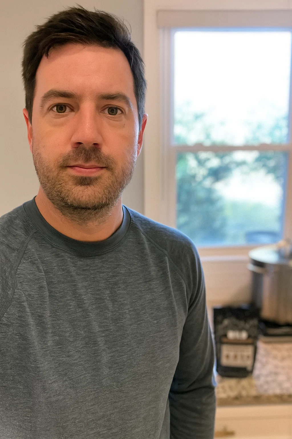 Person indoors with light blue shirt, background shows a window and kitchen items.