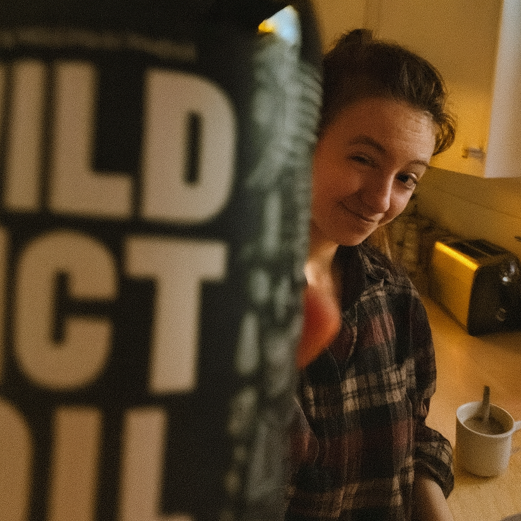 Person in a kitchen with a blurred container reading 'WILD __CT OIL' in the foreground.