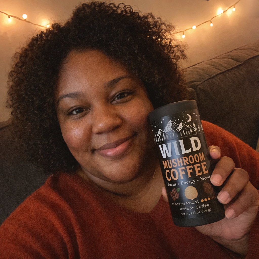Person holding a can of wild mushroom coffee, sitting on a couch with string lights in the background.