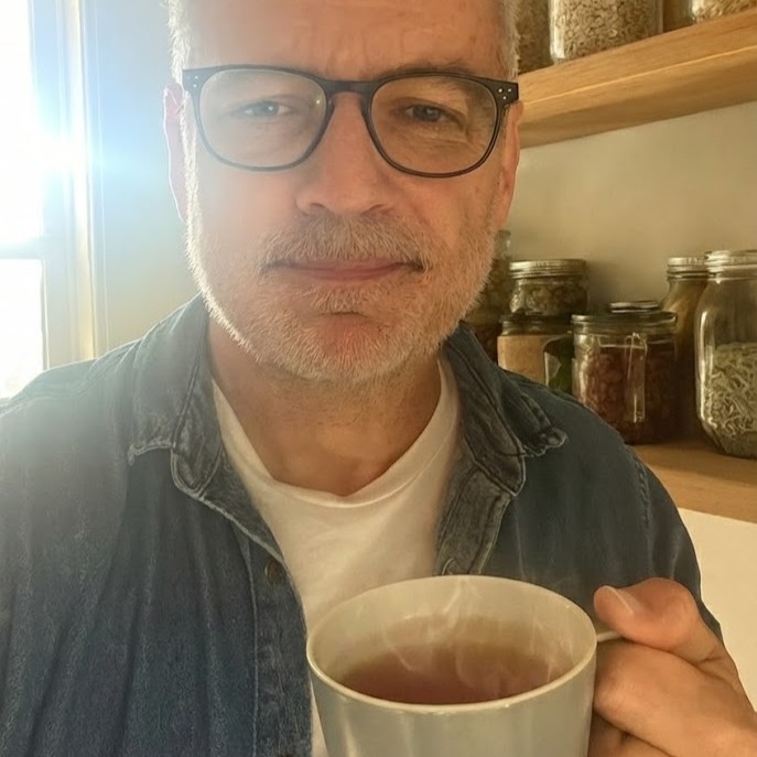 Person holding a mug with shelves of jars in the background.