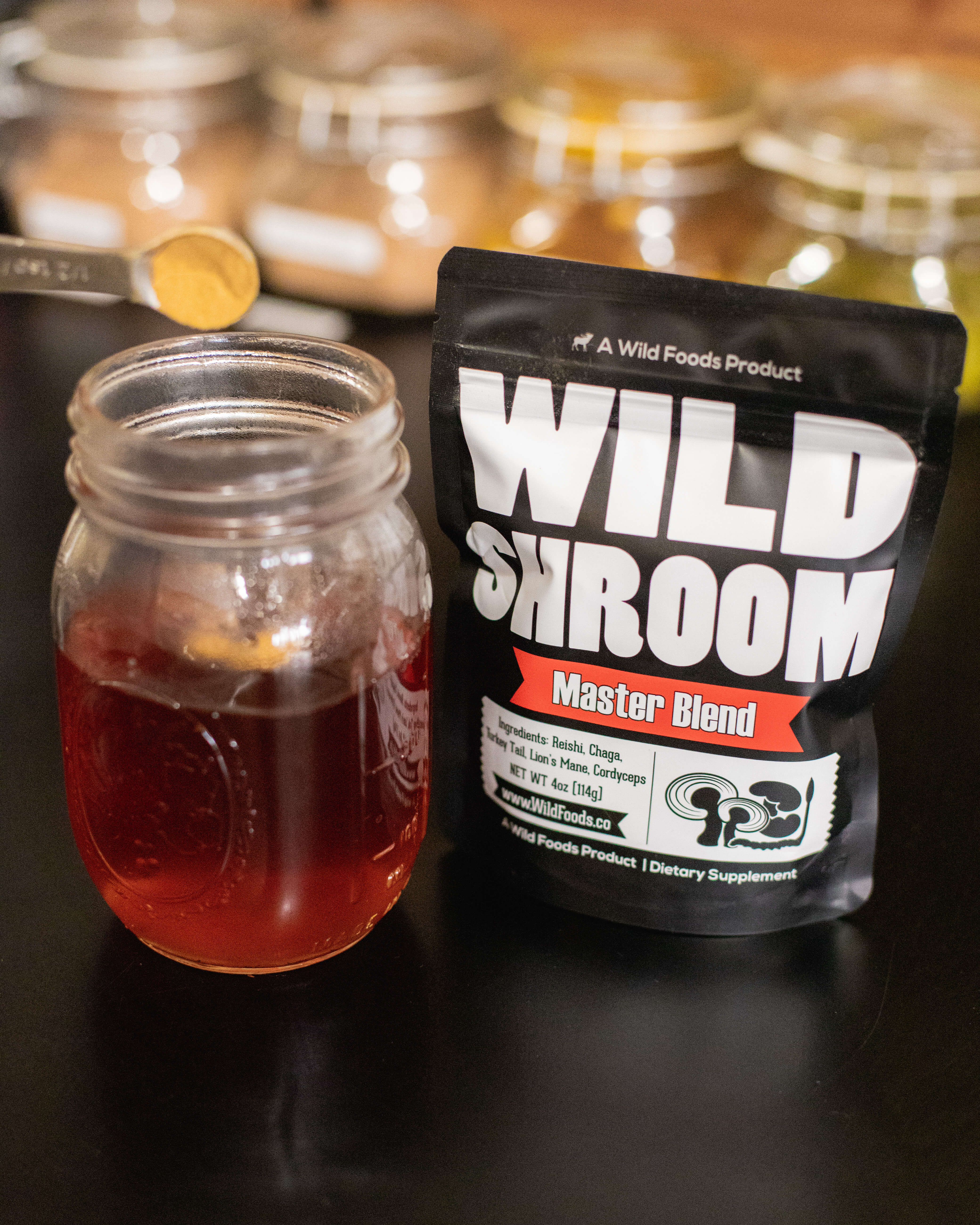 A jar of red liquid beside a black bag labeled 'Wild Shroom Master Blend'.