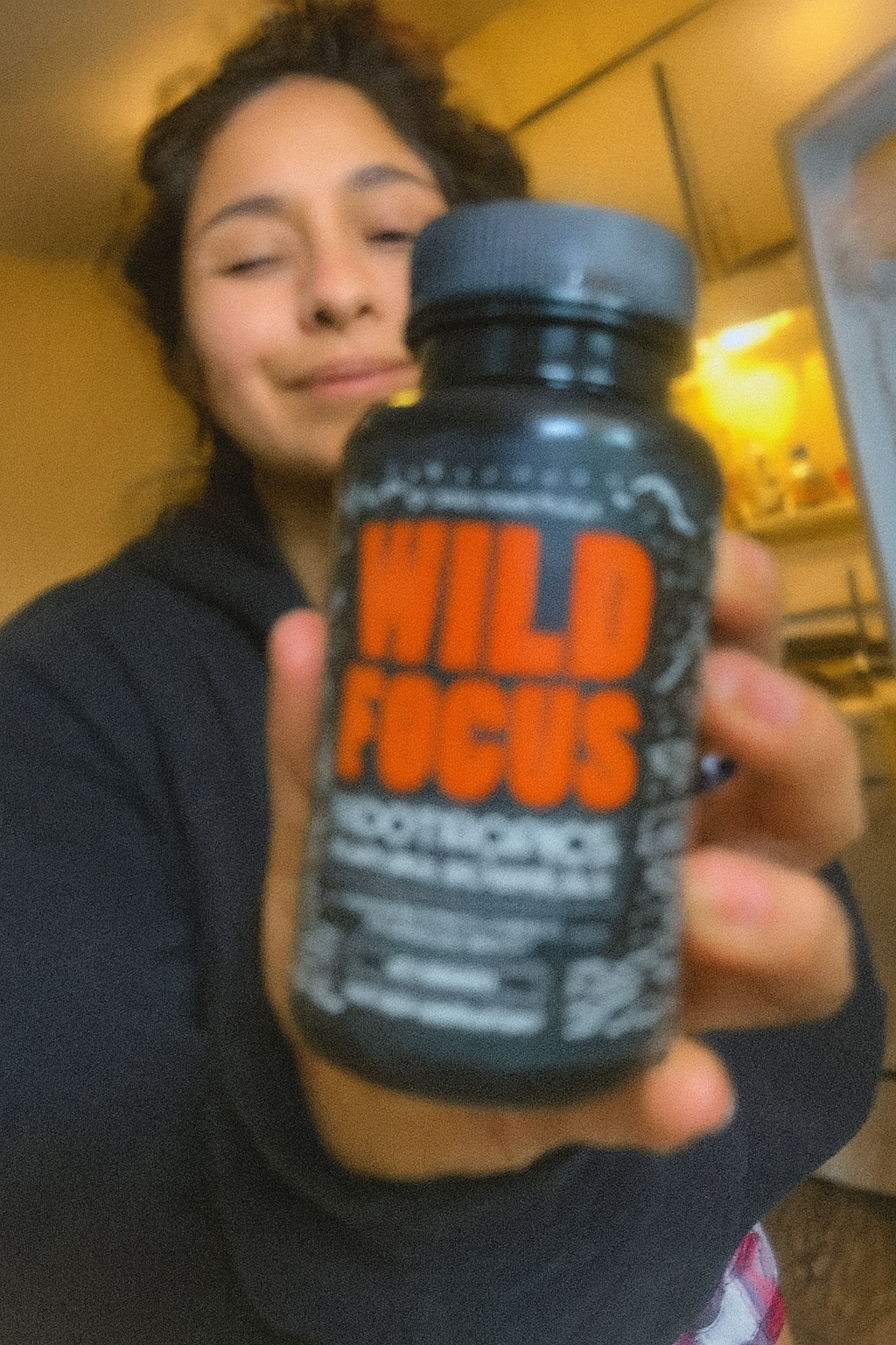 Person holding a bottle labeled 'Wild Focus' out of focus.