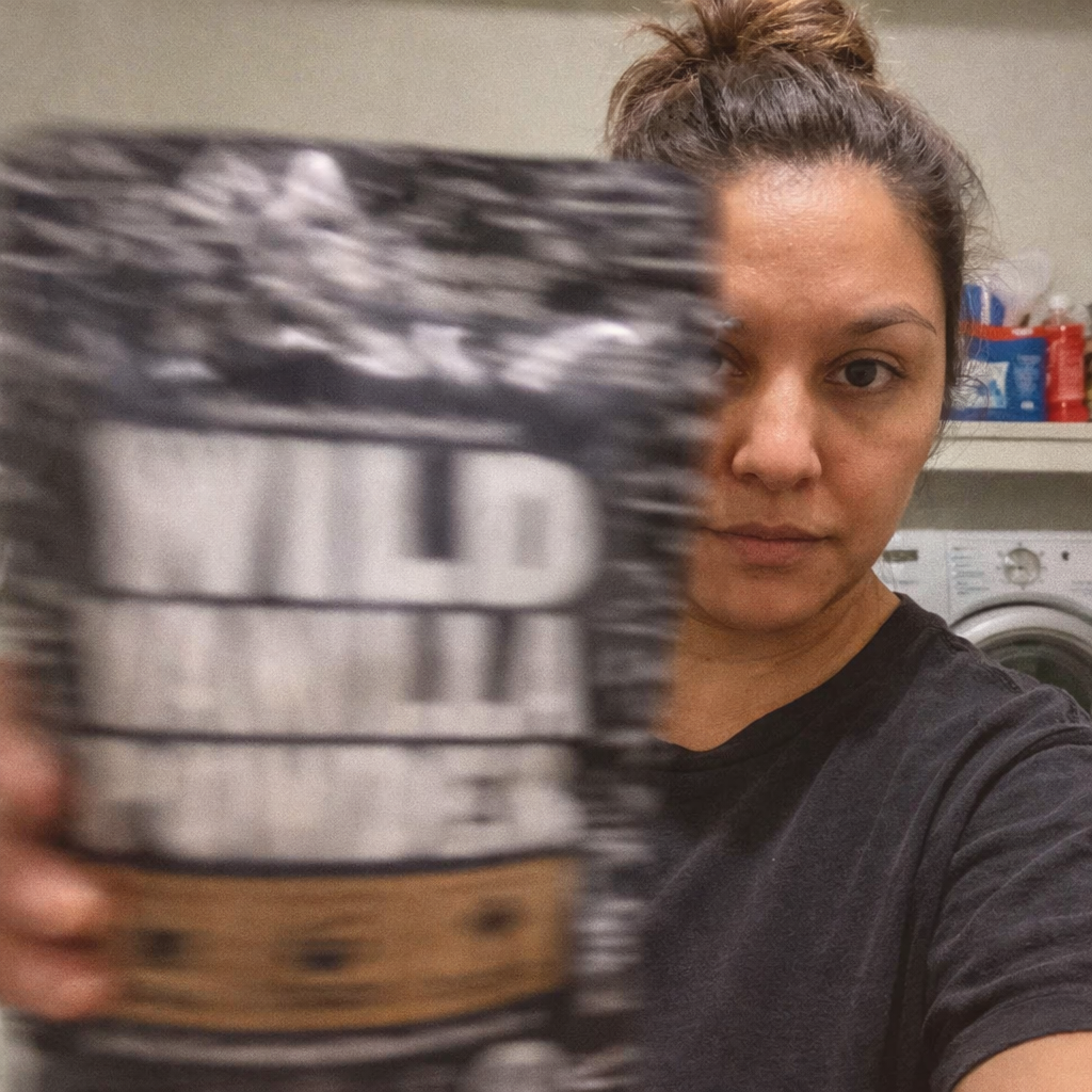 Person holding a bag labeled 'Wild Vanilla Powder' with a blurred background.