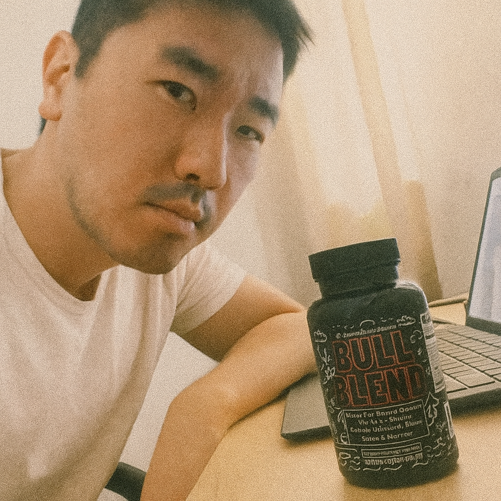 A person sitting at a desk with a laptop and a bottle labeled 'Bull Blend'.