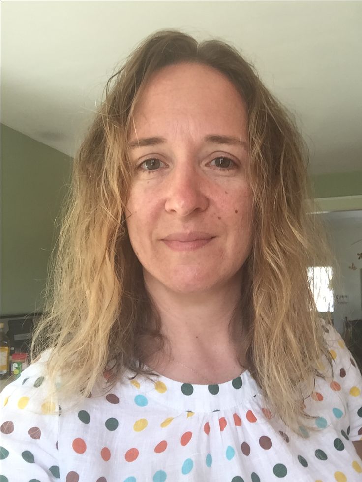 Person with wavy hair wearing a polka dot shirt.