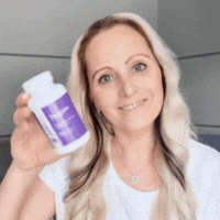 Person holding a bottle with a purple label, smiling at the camera.