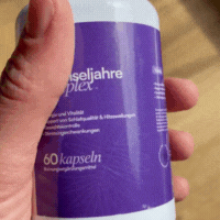 Hand holding a bottle with a purple label and text in German.