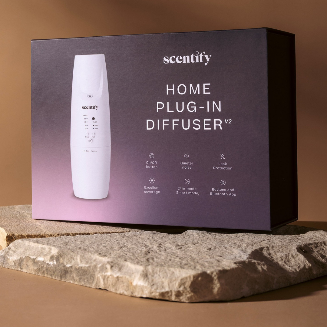 Box of a home plug-in diffuser on a textured stone surface.
