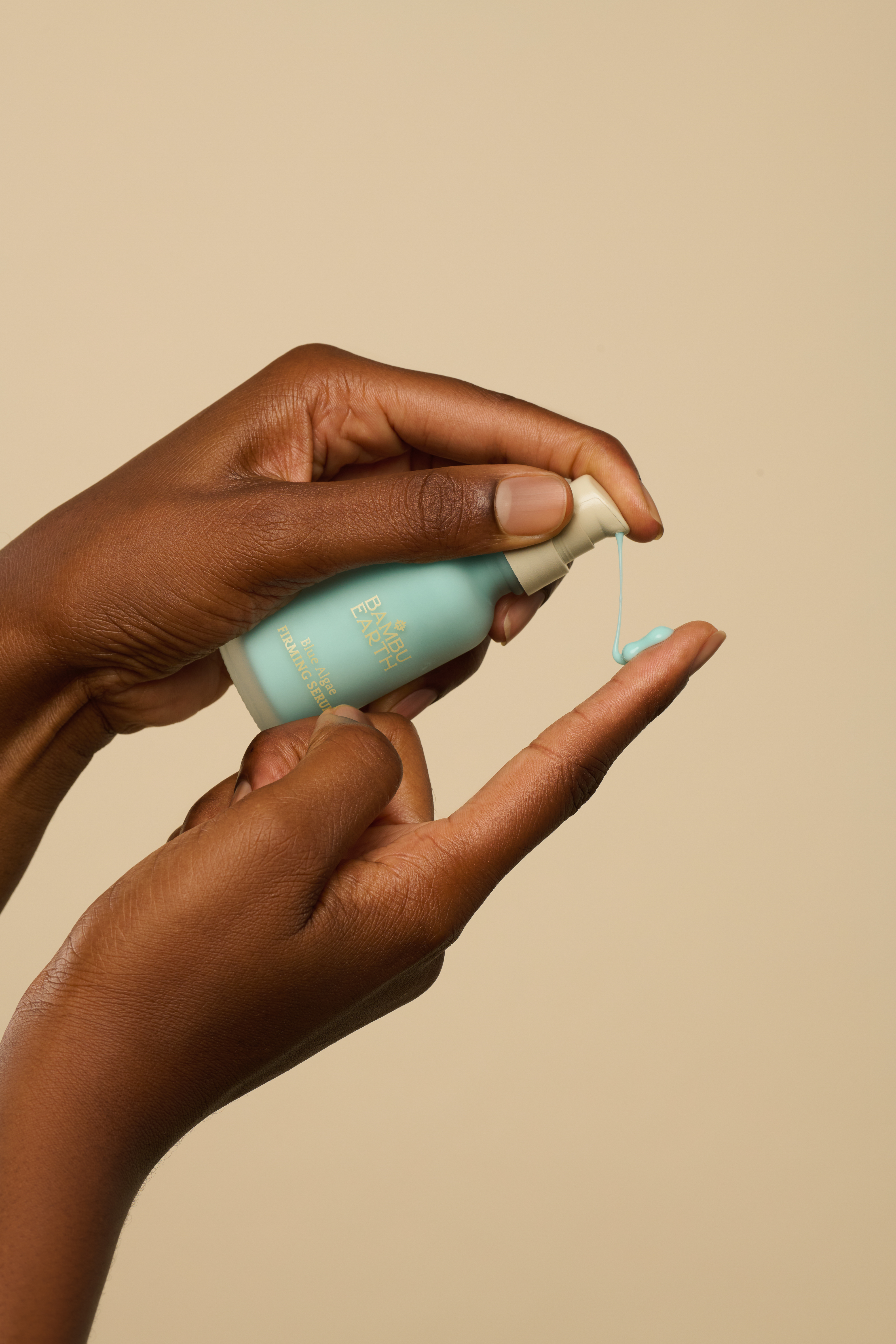 Hands dispensing serum from a small bottle.