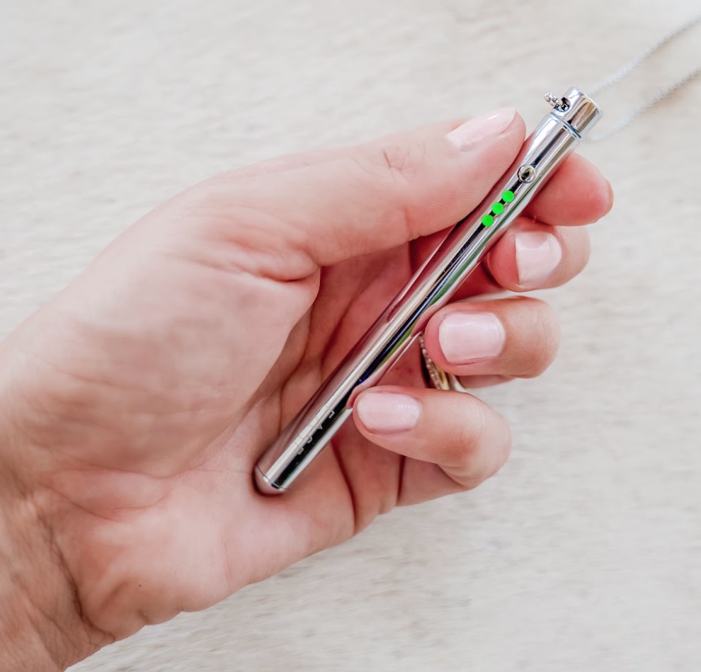 Hand holding a silver pen with green lights on it.