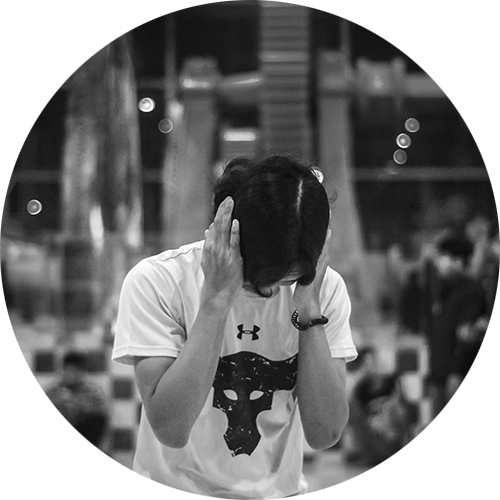 Person in a t-shirt covering ears in a blurry indoor setting.