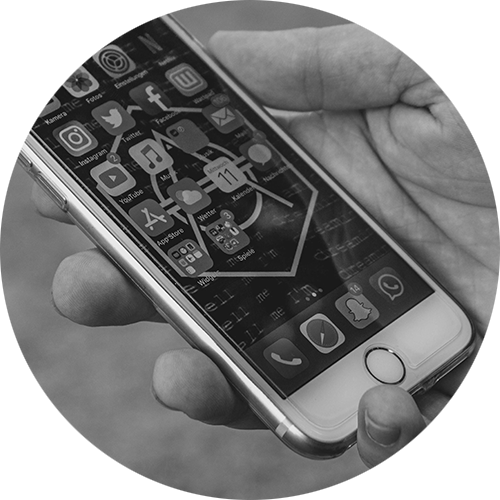 A hand holding a smartphone displaying various social media app icons.