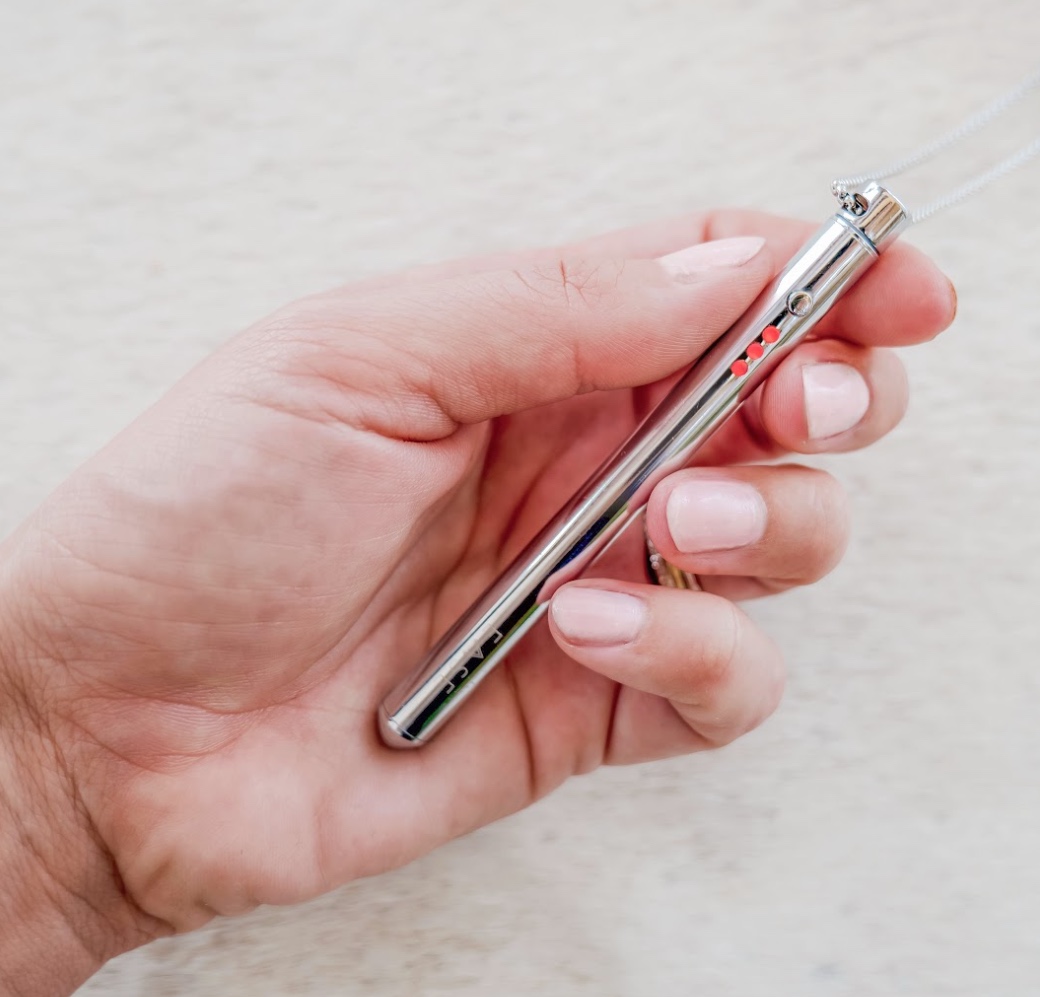 Hand holding a silver pen-like object with red accents.