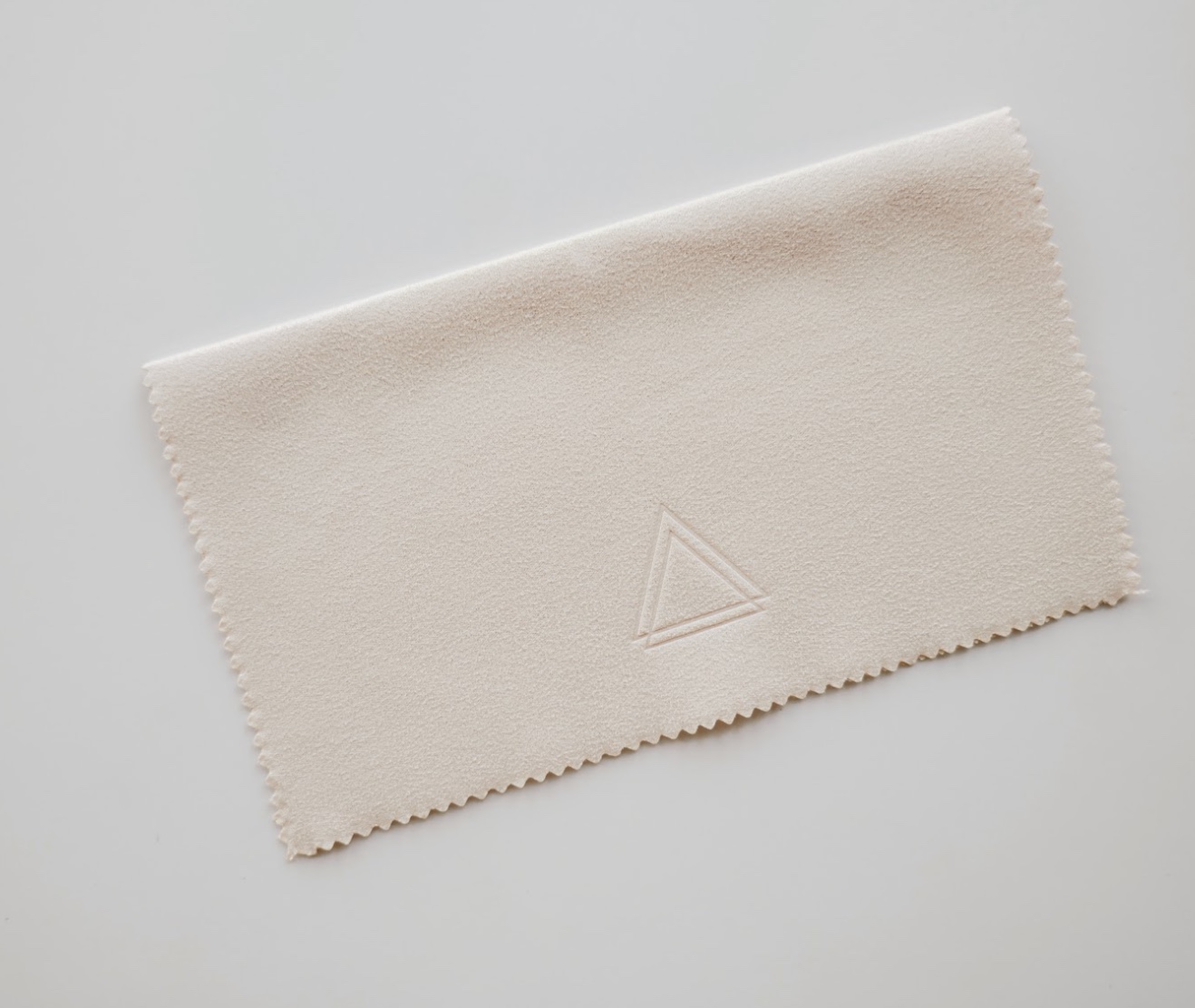 Beige microfiber cloth with a triangle logo embossed in the center.