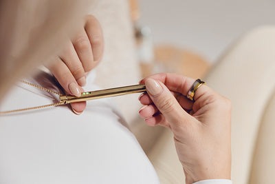Person holding a gold pen with both hands, wearing a ring.