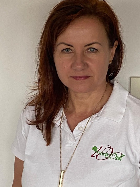 Person wearing a white polo shirt with embroidered text and a necklace.