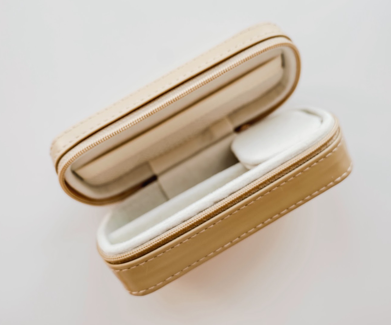 Open beige jewelry box with a soft interior lining.