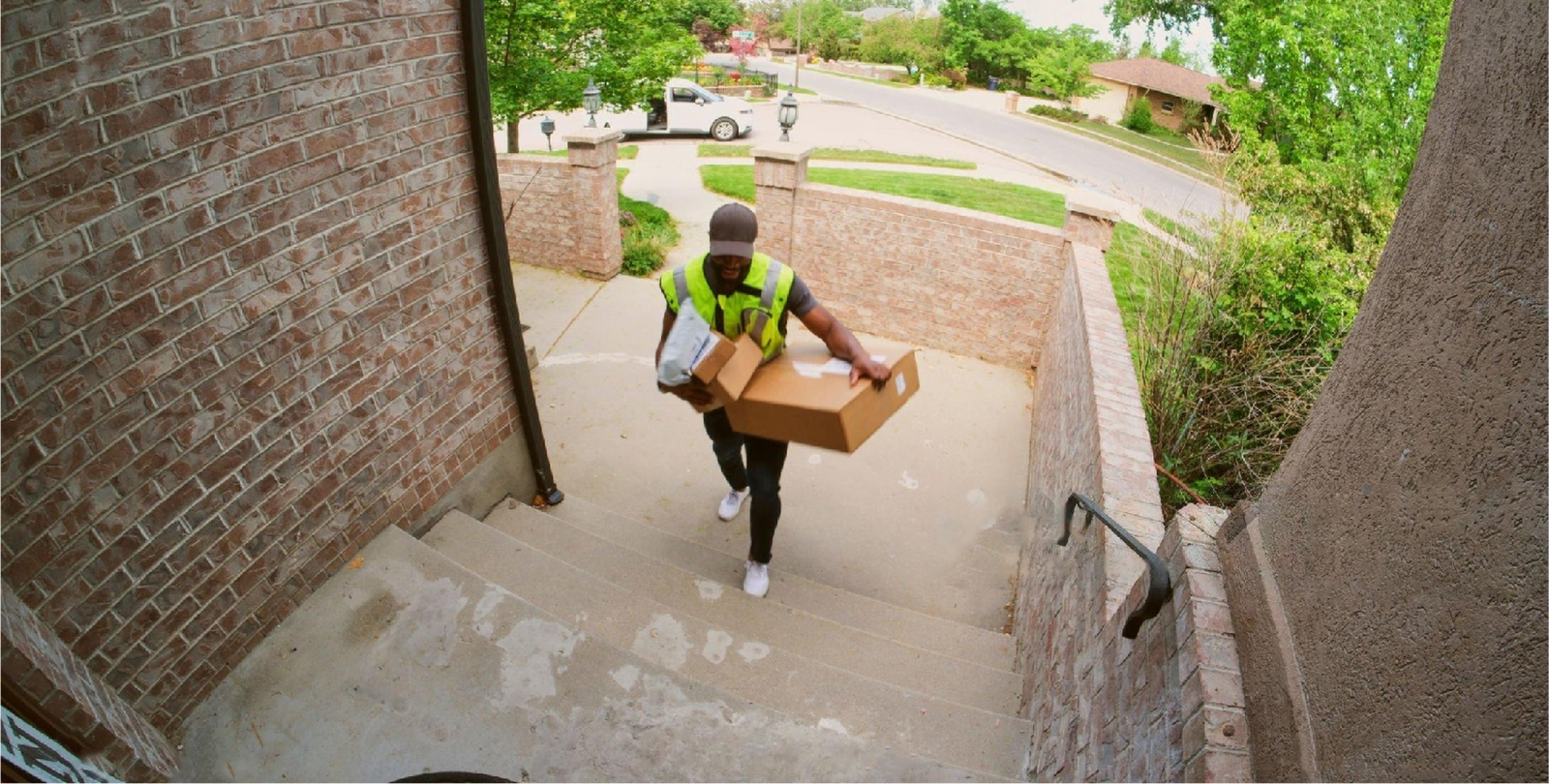 Delivery person carrying packages up a residential staircase.