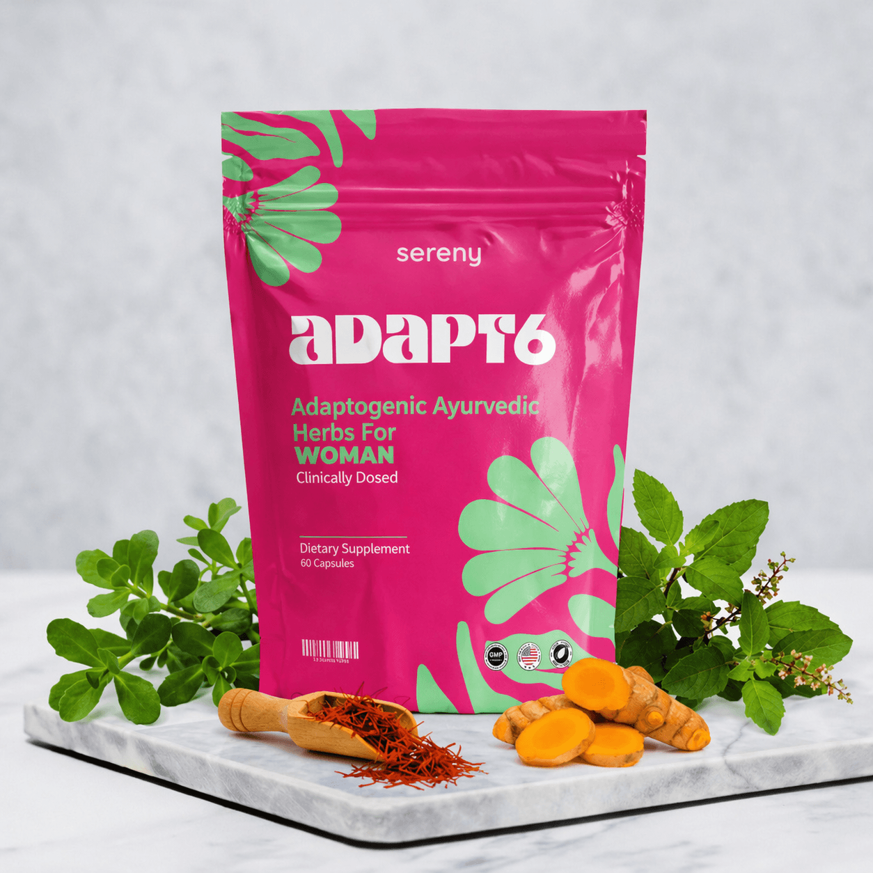 A pink pouch of Sereny ADAPT6 supplement on a marble slab with herbs, turmeric, and saffron.