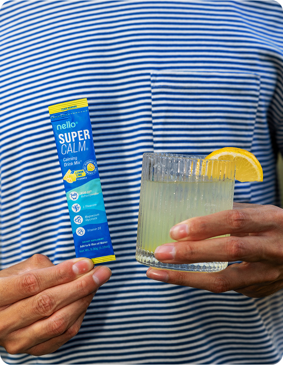 Person holding a drink mix packet and a glass with lemon slice.