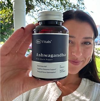 Person holding a bottle of Ashwagandha supplement outdoors.
