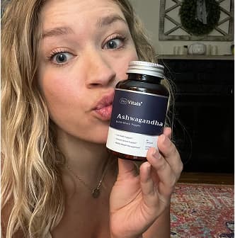 Person holding a bottle labeled 'Ashwagandha' and making a kiss face.